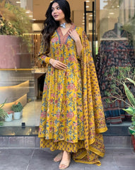 Woman in a yellow floral dress standing in front of a store entrance.